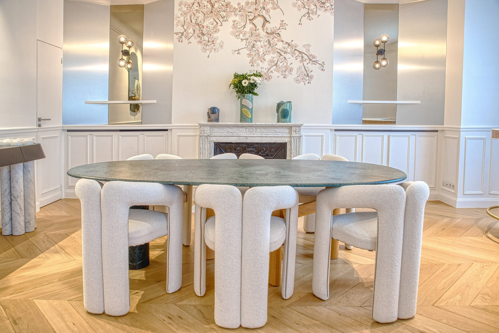 Salle à manger avec table ronde, chaises bouclées et cheminée en marbre