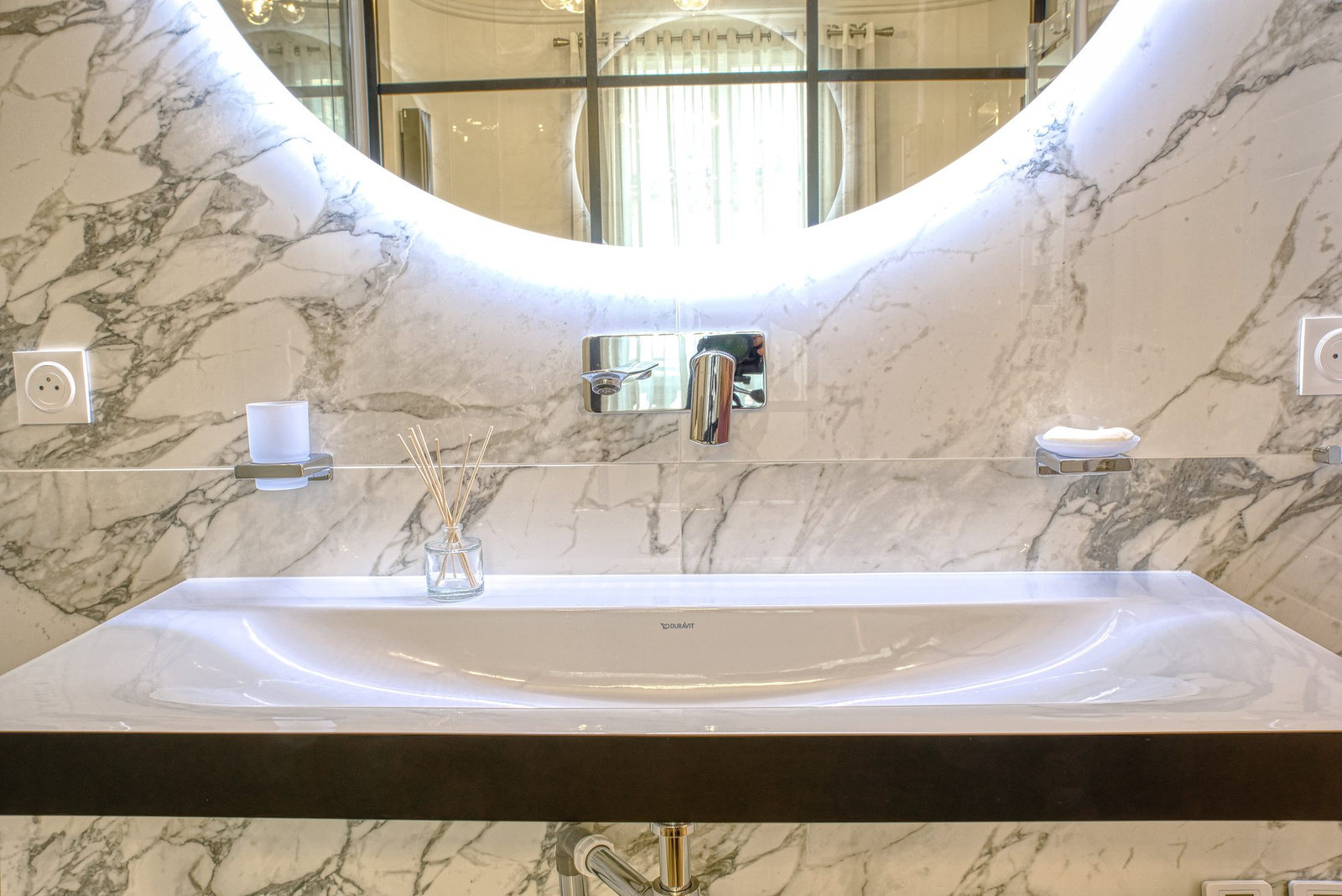 Salle de bains en marbre : baignoire encastrée et miroir rond rétroéclairé