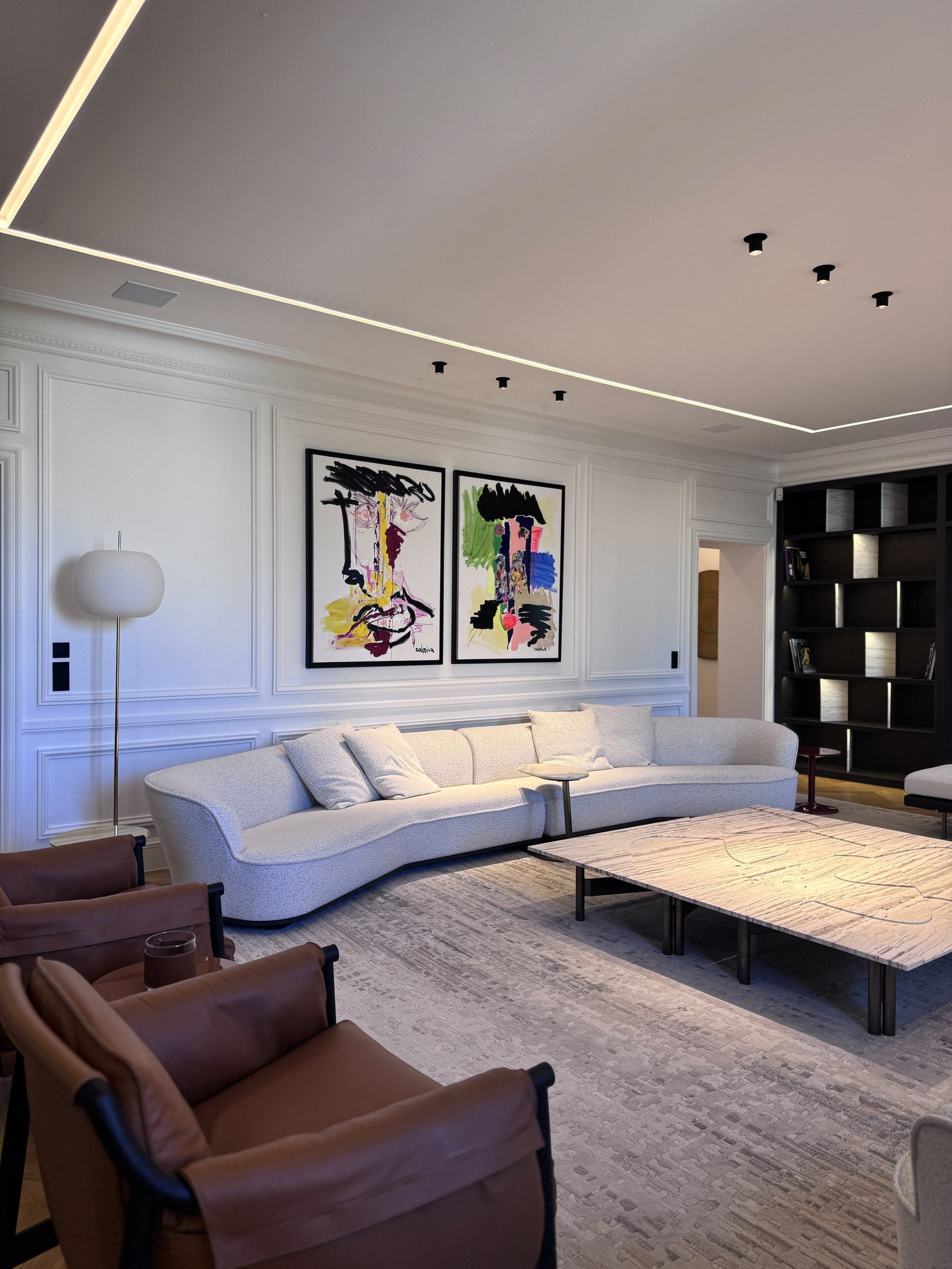 Séjour du duplex Maubourg avec canapé courbe, fauteuils en cuir et bibliothèque sur mesure