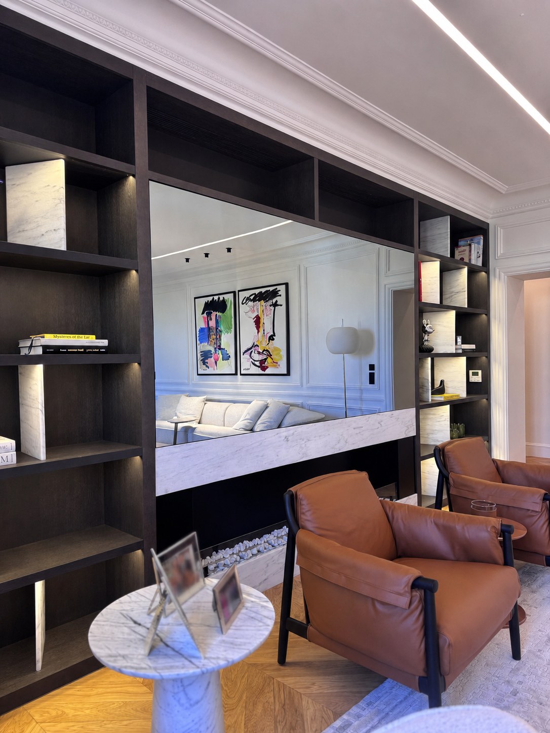 Bibliothèque sur mesure du duplex Maubourg, fauteuils en cuir et grand miroir