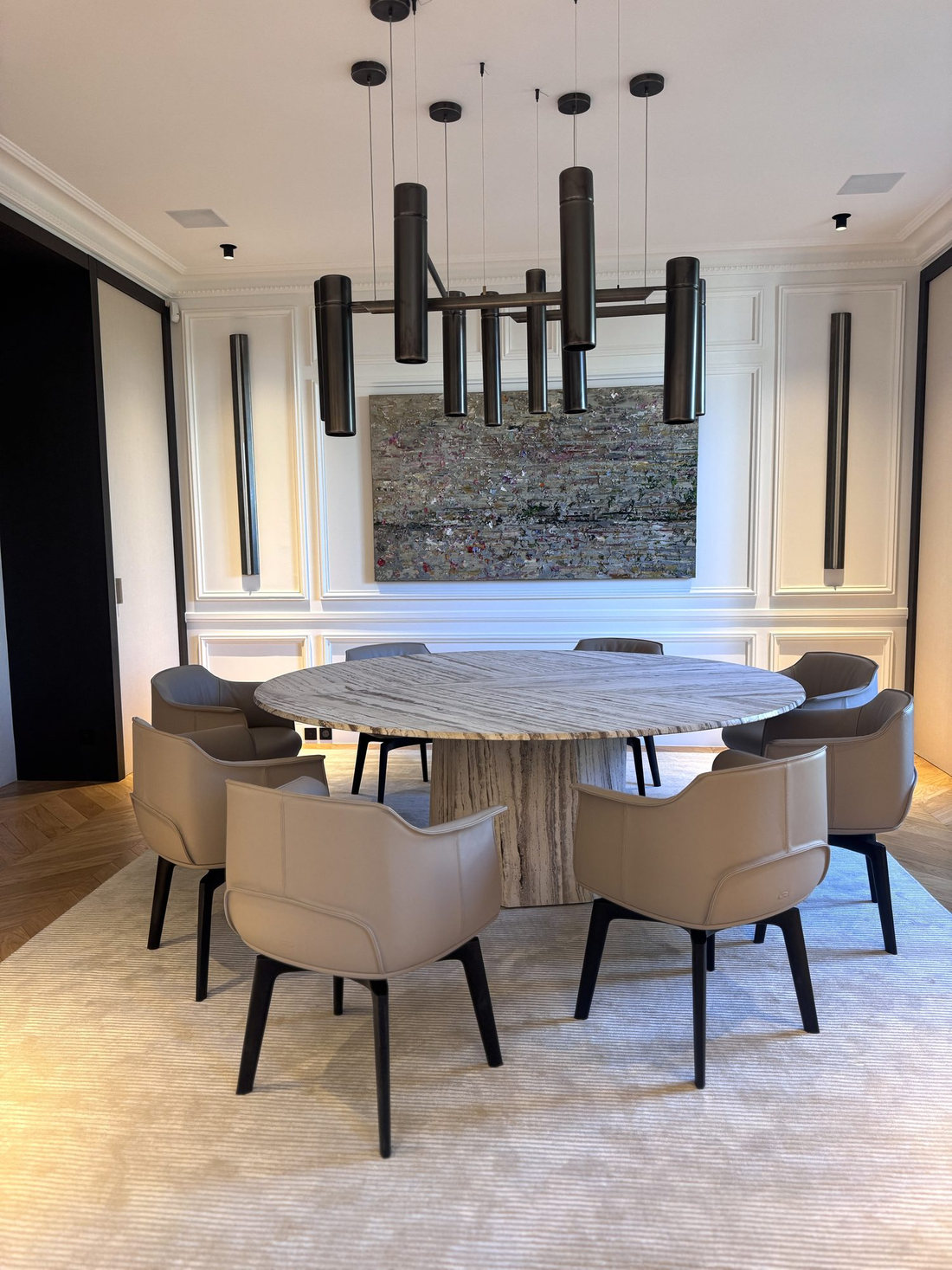 Salle à manger du duplex Maubourg avec table ronde en pierre et suspension linéaire