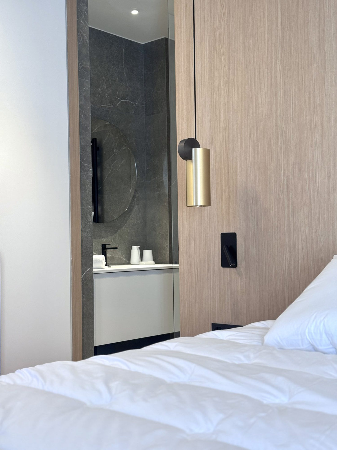 Détail de la tête de lit du duplex Périer, suspension en laiton et salle d’eau entrevue