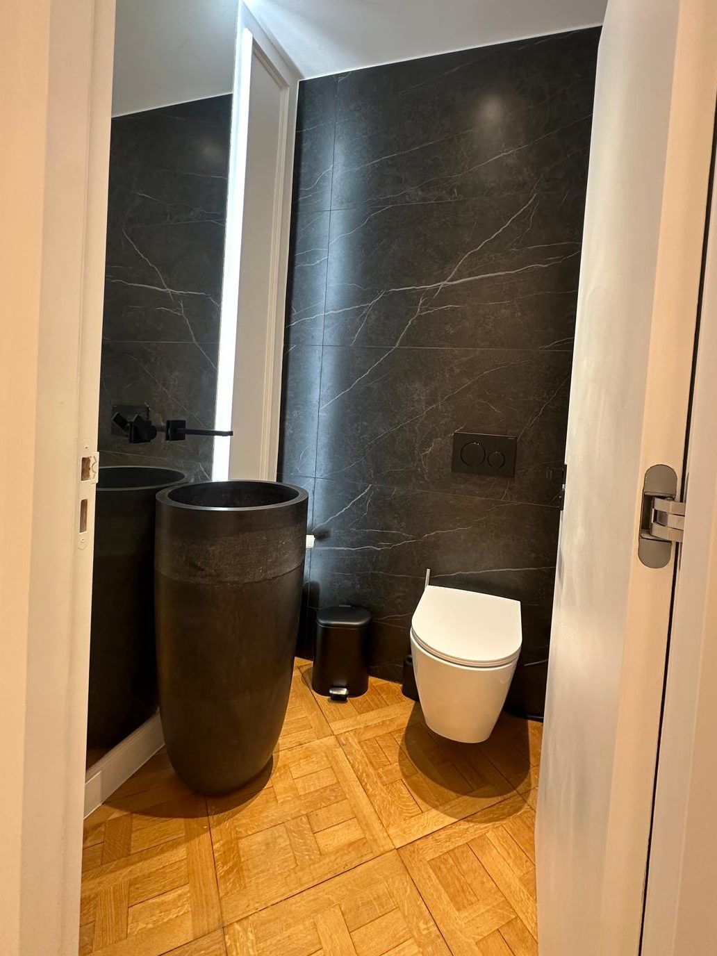 WC invité du duplex Périer : vasque totem sombre, WC suspendu et mur en pierre noire