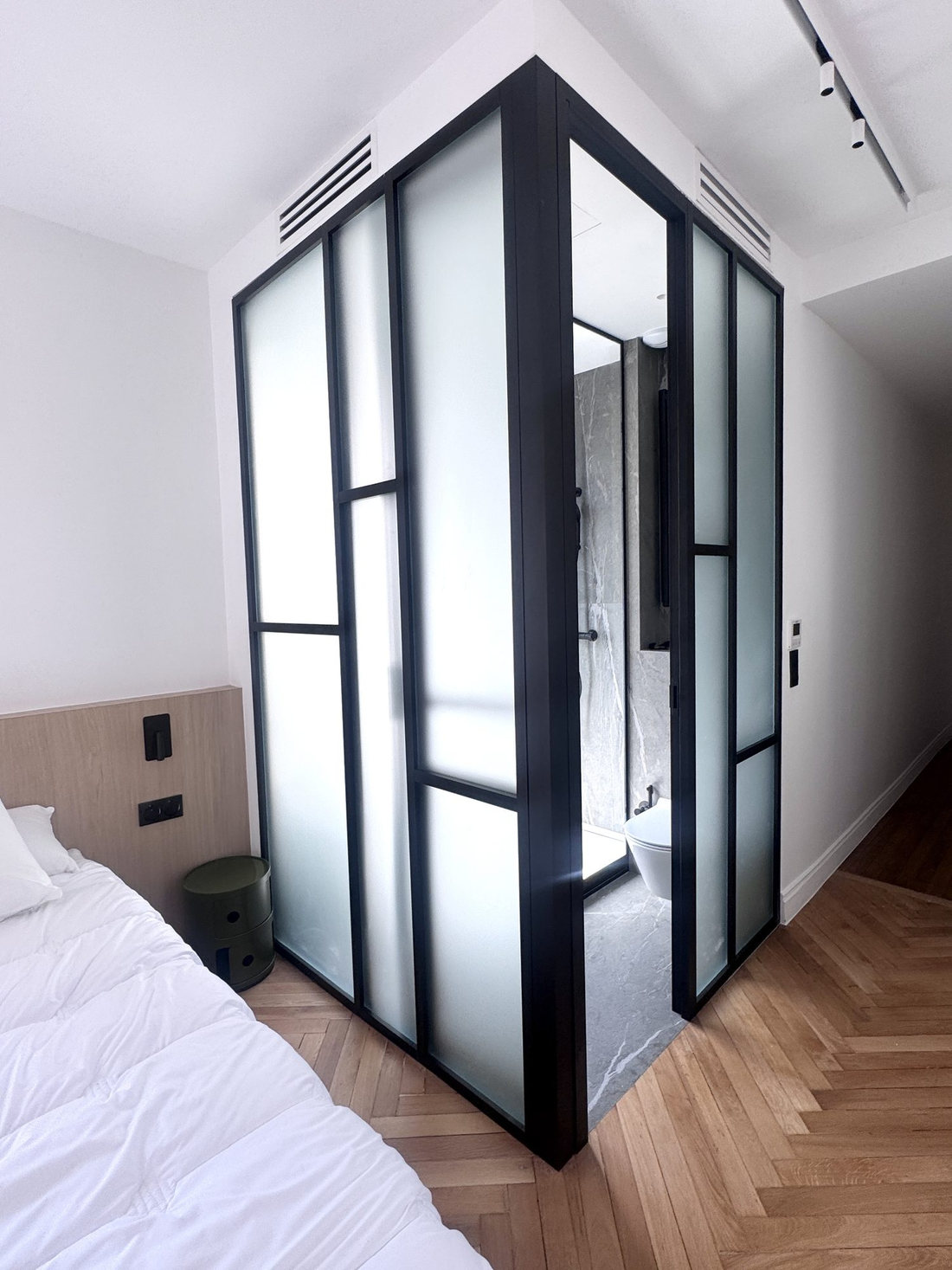 Salle d’eau du duplex Périer intégrée à la chambre dans un volume vitré à structure noire