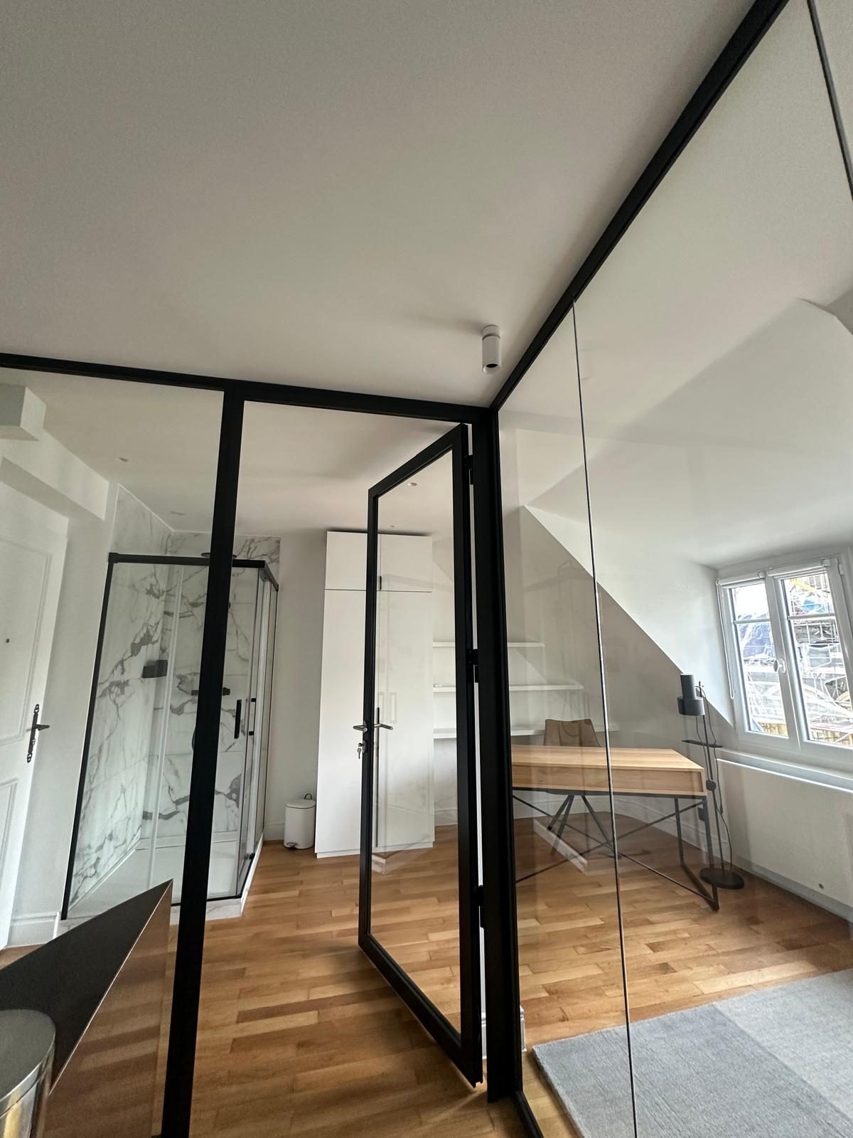 Espace sous pente du duplex Périer : paroi vitrée noire et bureau